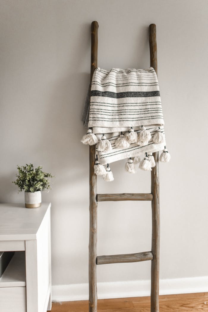 our-story-02 A modern decorative ladder with a hanging blanket in a cozy home setting.